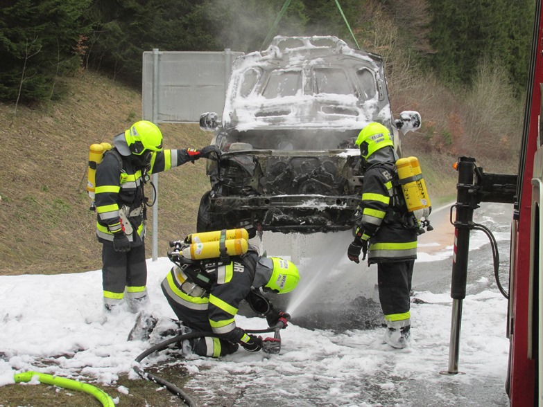 Feuerwehrler mit Atemschutz beim löschen eines Pkws 