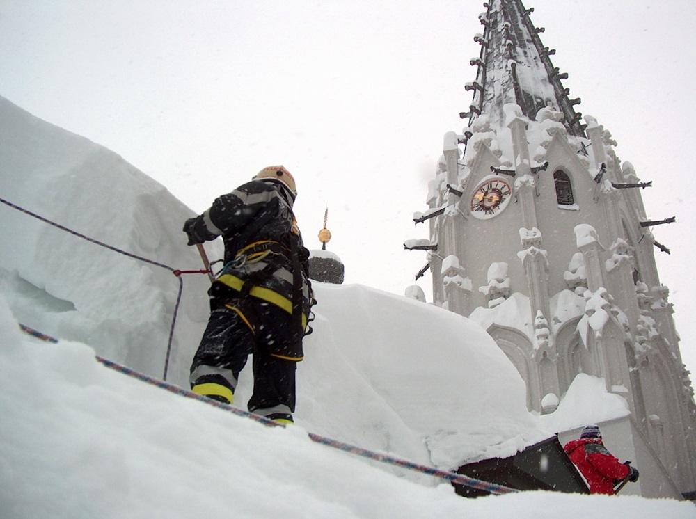Ein Feuerwehrler steht gesichert durch Seile am Dach der Basilika Mariazell