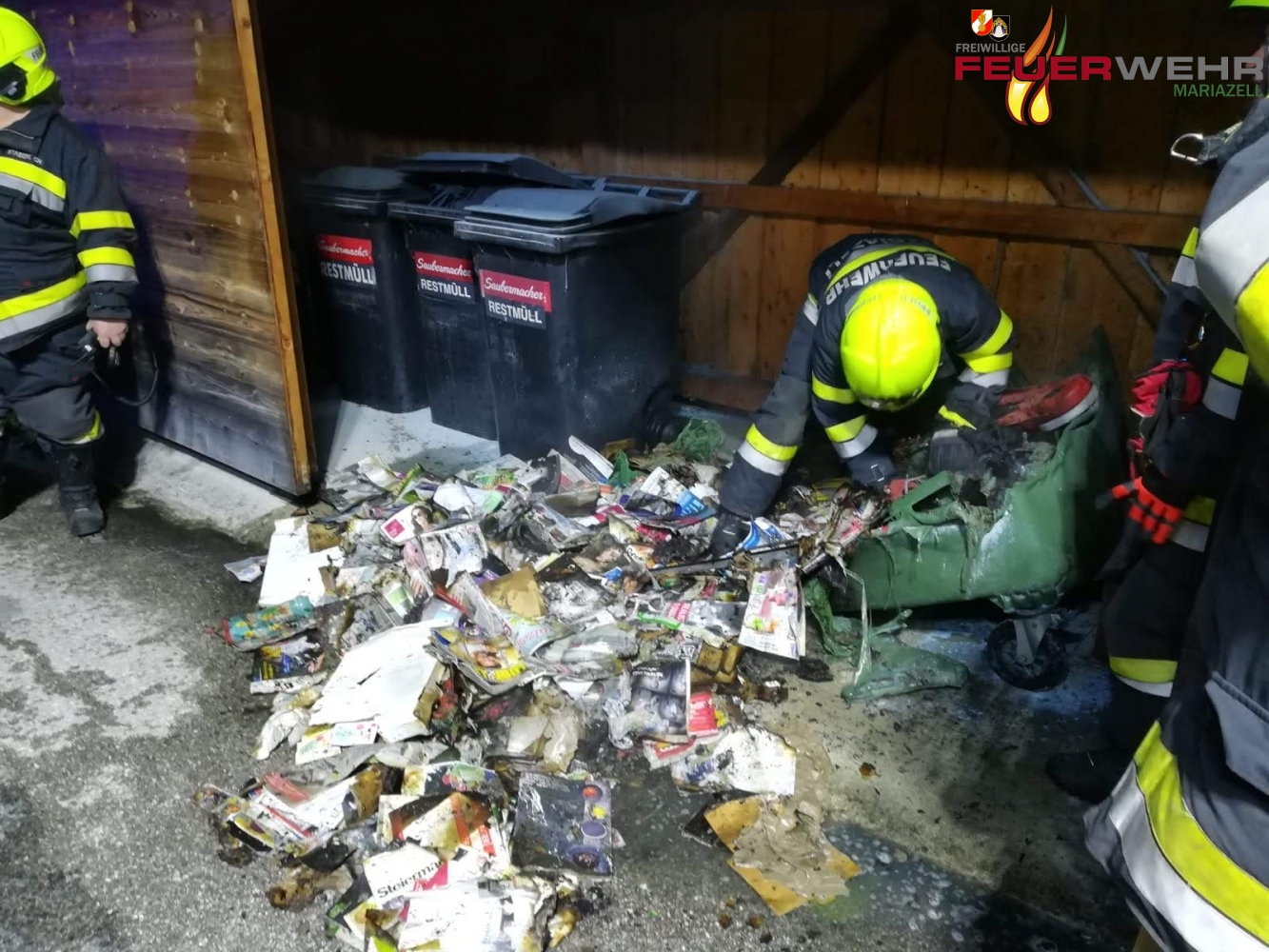 Feuerwehrmann mitten im Papiermüll und dem geschmolzenen Papiercountainer.